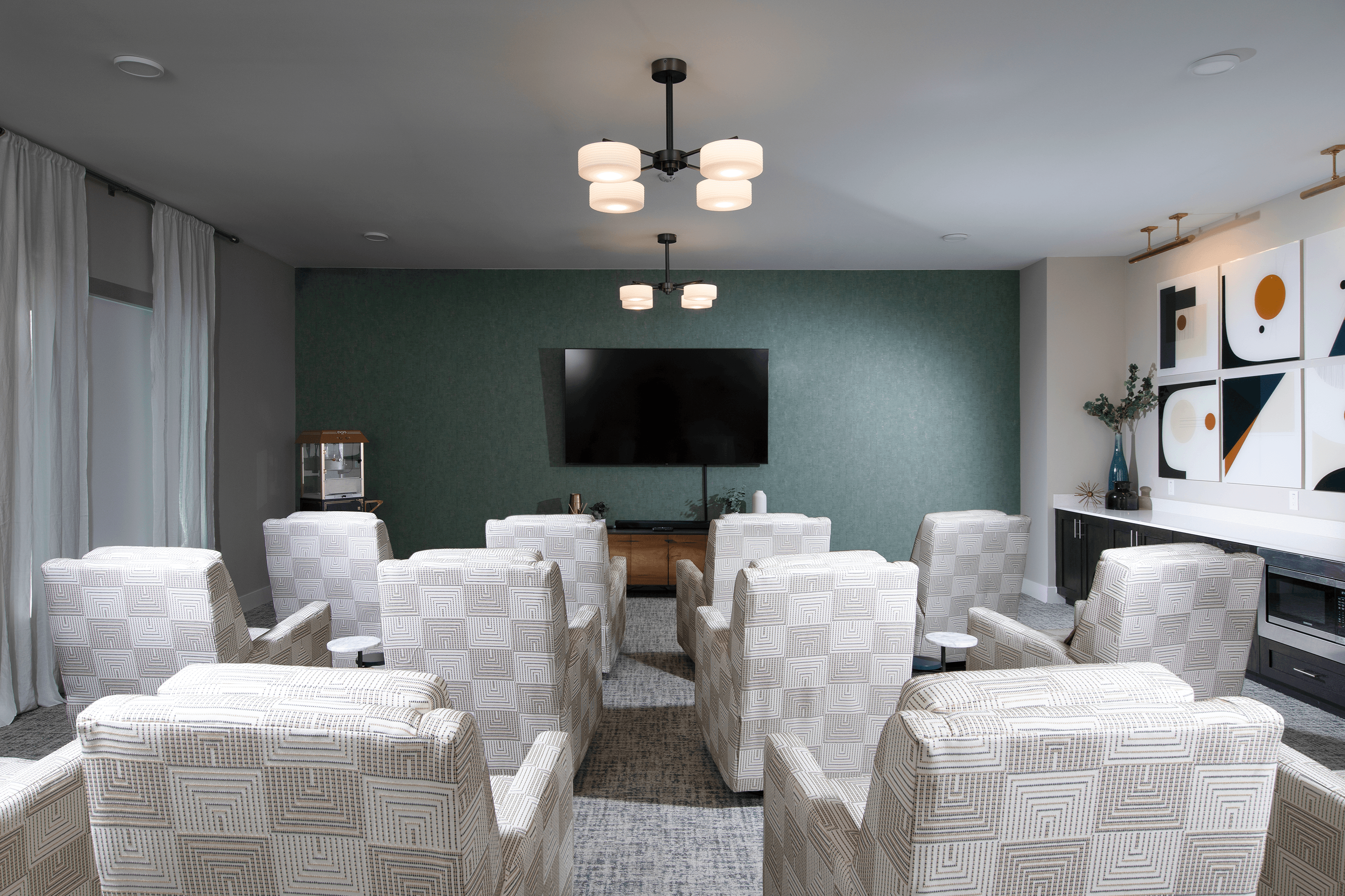 a media room with lounge chairs and a screen at a senior apartment community